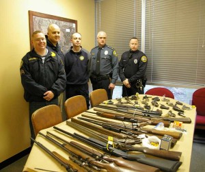 Police officers stand next to the guns collected during Saturday's gun buyback. The department collected 38 guns, a combination of shotguns, rifles, pistols, and ammunition. The department hopes that the collection will reduce the number of firearms available to potential criminals as well as reducing the number of crimes related to acquiring those guns.