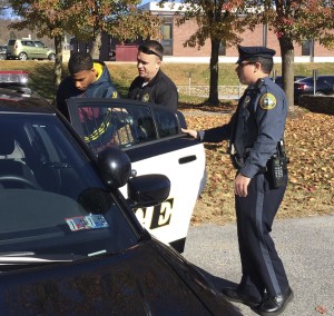 Zane Robinson (from left) is placed in a patrol car by Coatesville Det./Sgt. Brandon Harris and Officer Carmen Mollichella for transport to his arraignment Thursday on robbery charges.