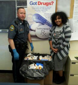 Officer Rodger Ollis and Coatesville Youth Initiative Drug Free Communities coordinator Lula Defersha stand next to over 60 lbs of drugs collected on Saturday.