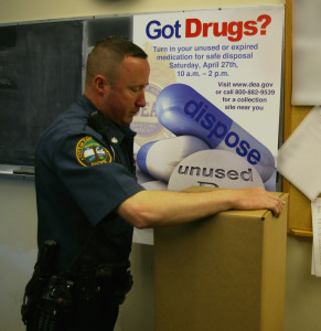 Officer Ollis secures a box of prescriptions with evidence tape.