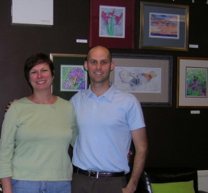 Lynda Pitcherella (left) poses with Dr. Matt Lapp and her work, which is on display at Salus Chiropractic Studio in Thorndale.