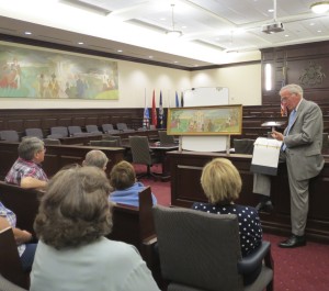 Chester County Court Judge Thomas G. Gavin discusses what little information is known about the 1956 mural by Edward Shenton. Behind him is the model painting that differs in numerous small ways from the finished product, now on the wall in Courtroom Two of the Chester County Justice Center.