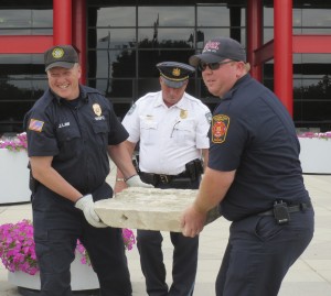 West Bradford Fire Chief Jack Law (left) and Malvern Fire Chief Neil Vaughn hoist one of the stone artifacts as West Pikeland Township Police Chief Shane Clark watches their backs.