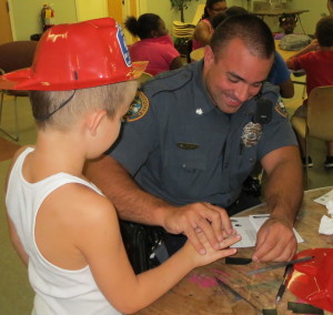Coatesville Police Officer Stephen Galletta demonstrates the fun of fingerprinting at "Fire Safety Day Camp."