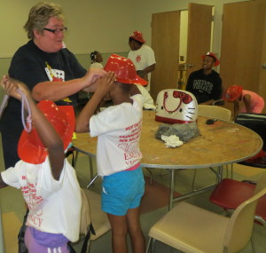 Kim Mattson, fire and life safety educator for the Thorndale Volunteer Fire Company, assists campers with their hats.