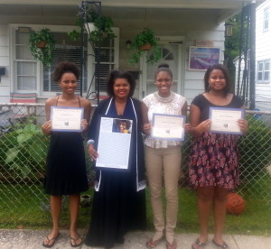 Scholarship recipients Shakira Lewis (from left), Sydney Coppadge, and Jocelyn Brown pose with Mildred L. Dixon (second from left), president of the Women’s Democratic Club of Chester County (WDCCC) in front of Gladys Flamer's Merchant Street home in Coatesville.