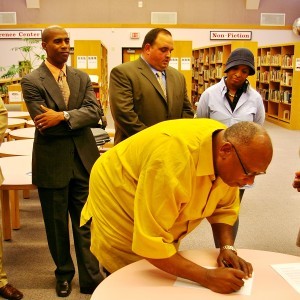 Pastor Randall Harris of the Coatesville Ministers Alliance signs the proclamation condemning discrimination in the Coatesville Area School District as NAACP Secretary Anthony Taylor, Acting Superintendent Angelo Romaniello, and Board Member Dr. Tonya Thames Taylor look on.