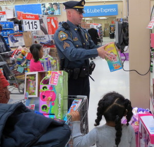 As the children eagerly await the results, Coatesville Sgt. Rodger Ollis uses the price-checker to help them stay within their budgets. 
