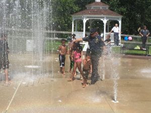 At the dedication of Coatesville's splash pad last week, Sgt. Rodger Ollis walked through the sprinklers with some children as Chief Jack Laufer looked on.